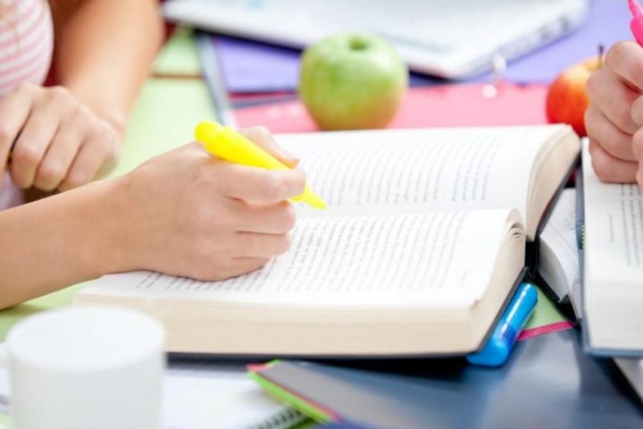 Girl reading a book and highlighting it with a yellow highlighter